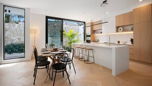Cozinha moderna com ilha central, banquetas e área de refeições com mesa e cadeiras.