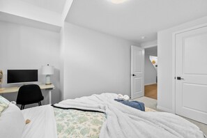 Une chambre d’hôtel comprenant un lit, un bureau avec un ordinateur, une chaise et une porte donnant sur une autre pièce.