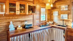 A wooden cabin interior with a kitchen counter, cabinets, and a hanging light fixture. - Nico's House (Lembongan Island)