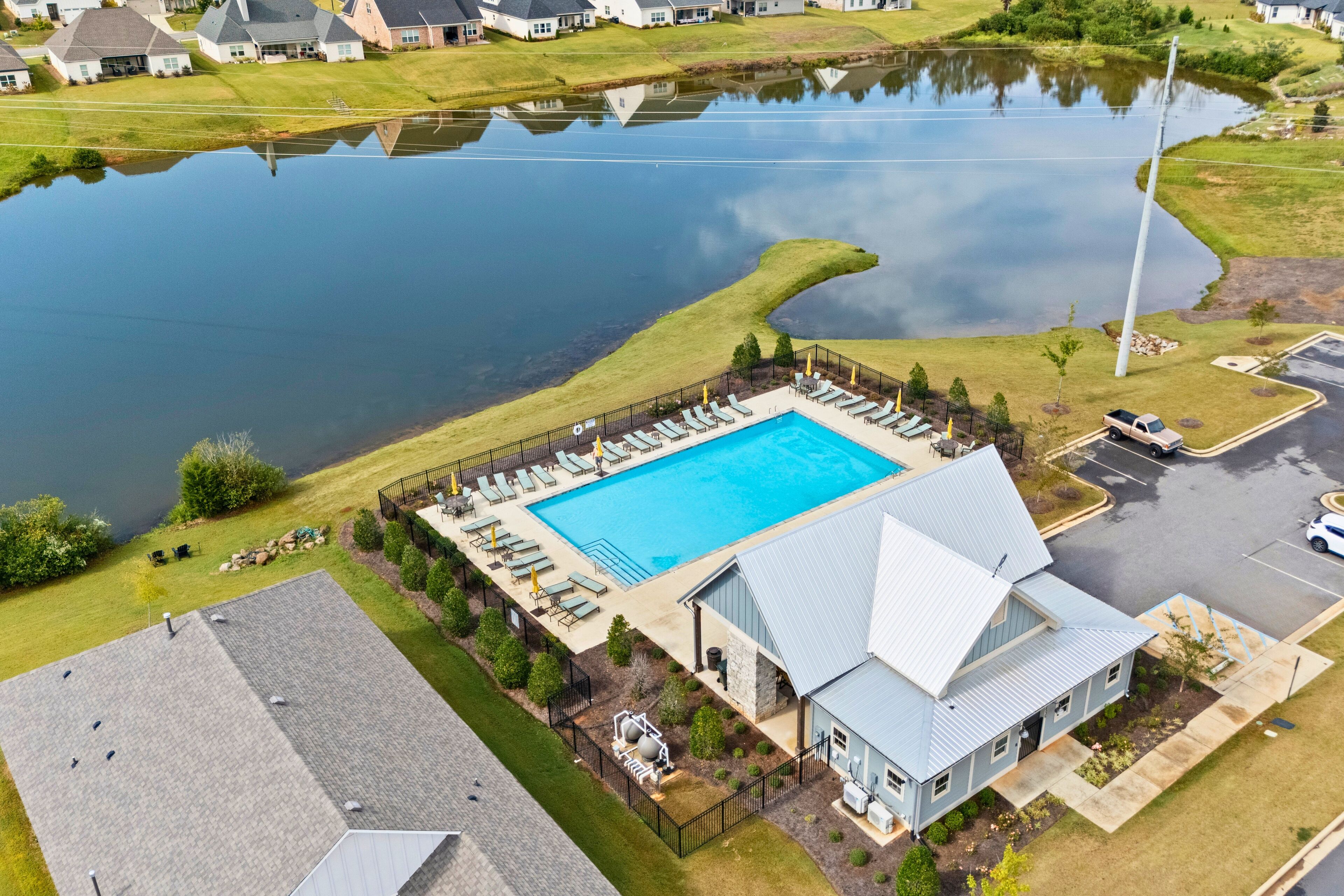 Oversigtsbillede af et boligområde med swimmingpool, liggestole og en mindre bygning.