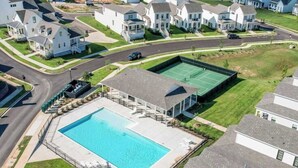 Un quartiere residenziale con una grande piscina, un campo da tennis e case.