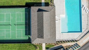 Vista aerea di una struttura con campo da tennis, piscina e area coperta.