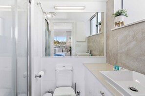 A modern bathroom with a glass shower enclosure, a toilet, and a sink with a marble countertop. - 2 Bedroom Ocean View in Tower at Burleigh Beach (Burleigh Heads)