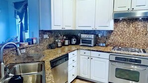 A modern kitchen with white cabinets, a granite countertop, a dishwasher, a stove, and a built-in oven. - Spacious & Cozy Home 3BD 2BA Near SF (Daly City)