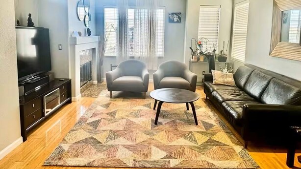 A living room with a sofa, two armchairs, a coffee table, a TV, and a fireplace. - Spacious & Cozy Home 3BD 2BA Near SF (Daly City)