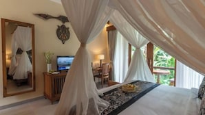 A bedroom with a bed, a TV, a desk, and a mirror. - The Compass Rose Ubud (Bali)