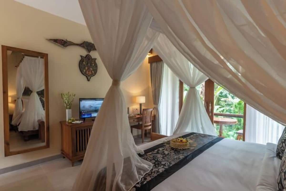 Un dormitorio con cama, televisión, escritorio y espejo.