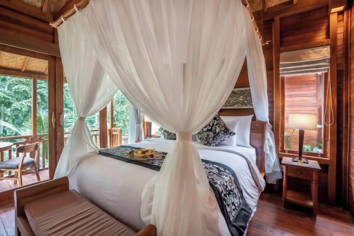 Una habitación con cama con dosel, una mesa de comedor y vistas al exterior.