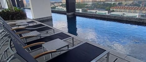 A rooftop pool area with lounge chairs and a view of a cityscape.