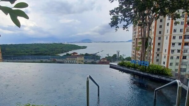 A swimming pool with metal railings, surrounded by greenery and buildings. - Aesthetic 2BR @ Urban Suite (Infinite Pool & Gym) (George Town)