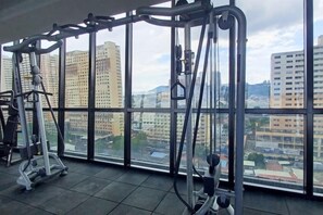 A gym with exercise equipment and a large window overlooking a cityscape. - Aesthetic 2BR @ Urban Suite (Infinite Pool & Gym) (George Town)