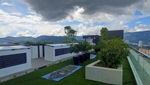A rooftop terrace with modern architecture, a grassy area, and potted plants. - Aesthetic 2BR @ Urban Suite (Infinite Pool & Gym) (George Town)