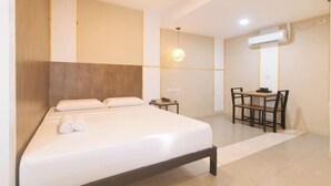 Une chambre d’hôtel avec un lit, un bureau et une chaise.