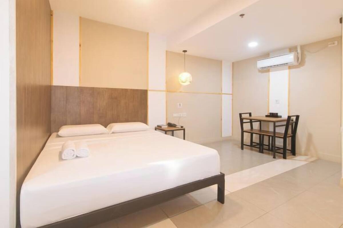 A hotel room with a bed, a desk, and a chair.