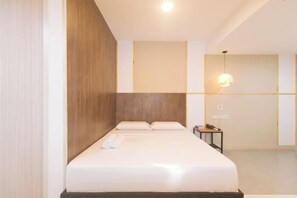 Een moderne hotelkamer met een groot bed, een houten hoofdbord en een nachtkastje met een lamp.