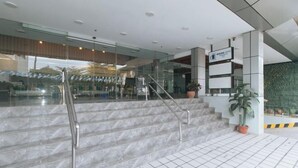 Un hall d’hôtel moderne avec des marches en marbre, des portes en verre et une enseigne indiquant « MAN CITY ».
