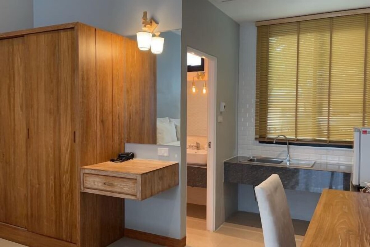Una cocina compacta con un lavamanos integrado, muebles de madera y una ventana con persianas.