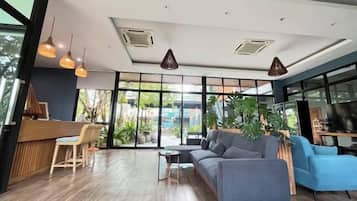 A modern interior with a reception desk, seating area, and large windows.