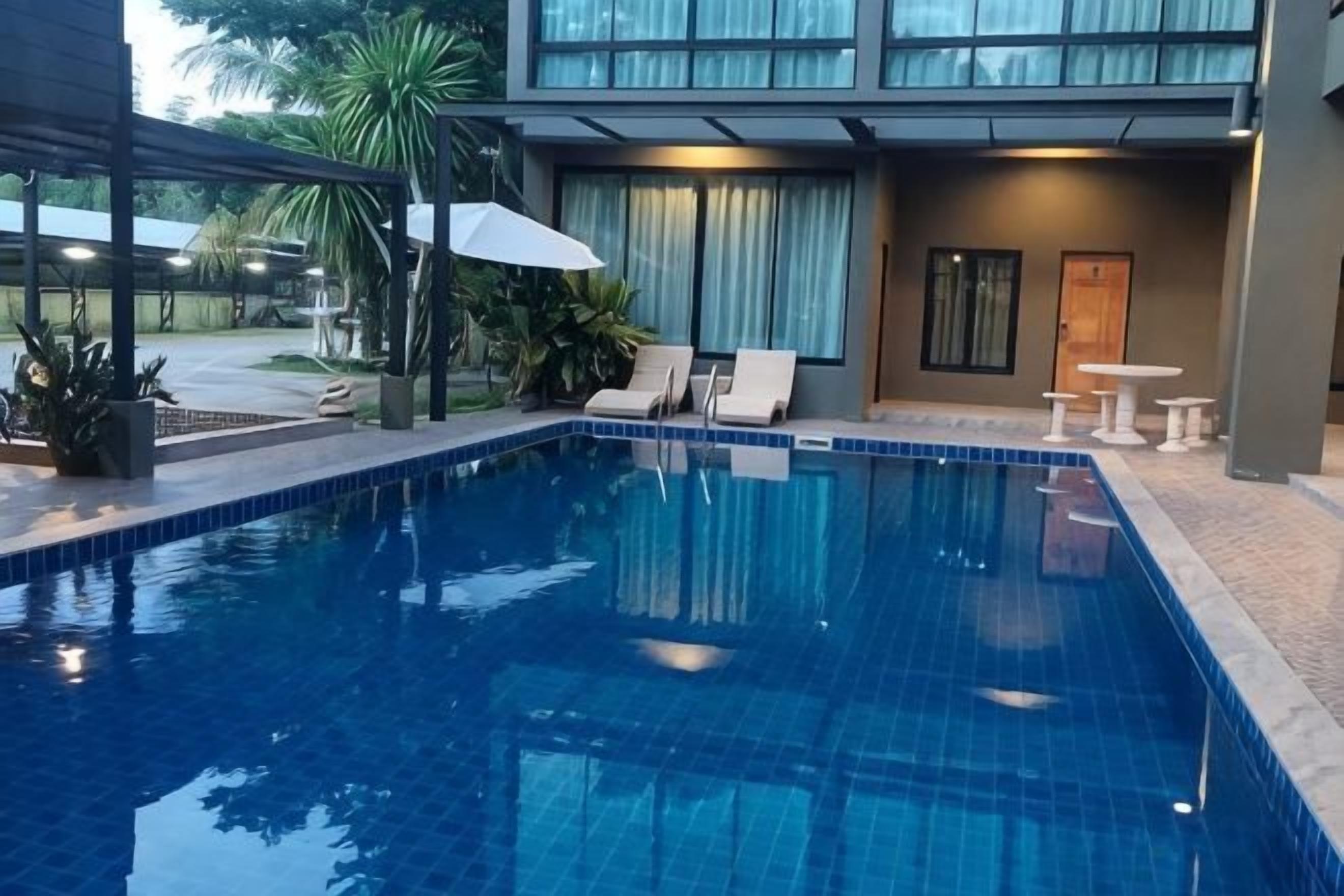 A swimming pool with lounge chairs and a covered seating area.