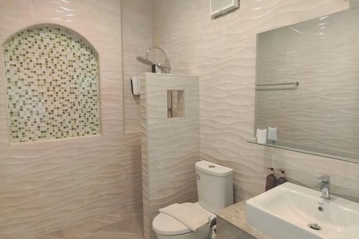 Un baño con pared de mosaicos, un inodoro, un lavabo y un espejo.