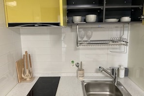 A kitchen with a stainless steel sink, a black countertop, and a yellow cabinet above. - OceanStay E7 INN-The City jukdo (Yangyang)