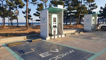 Electric vehicle charging stations with a clear view of the beach and trees in the background.