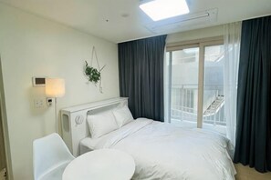 A hotel room with a bed, a bedside table, a chair, a window with curtains, and a balcony. - OceanStay E7 INN-The City jukdo (Yangyang)