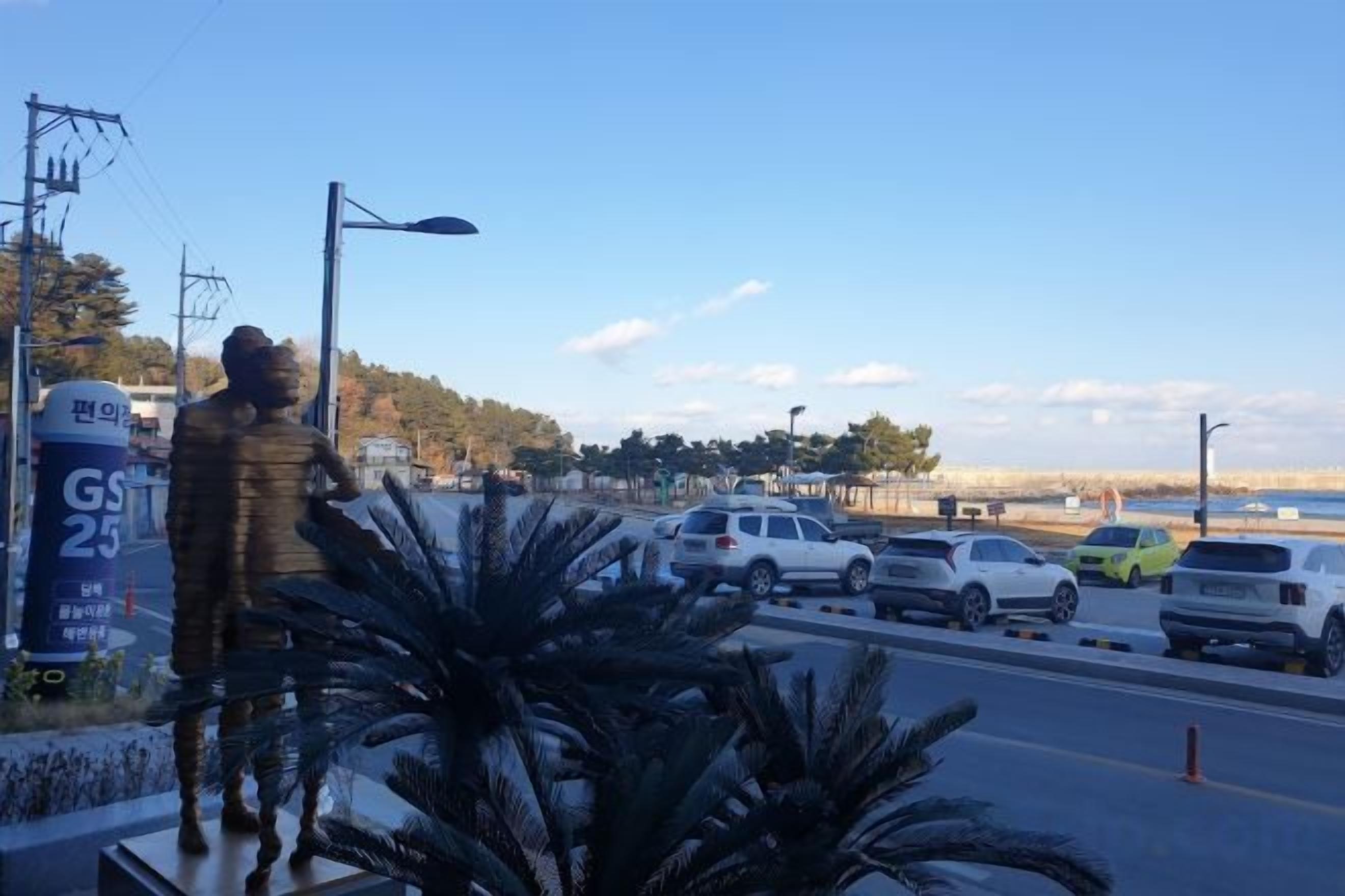 Un estacionamiento con automóviles, una estatua y un cielo despejado.