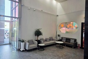 A modern lobby with a seating area, a large window, and a wall-mounted artwork. - OceanStay E7 INN-The City jukdo (Yangyang)