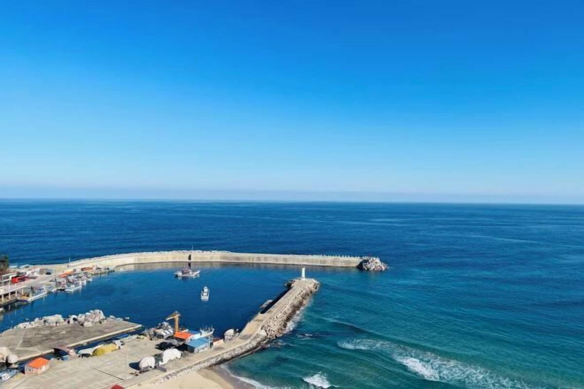 Ein Küstenhafen mit Booten, einer Pier und einem Leuchtturm.