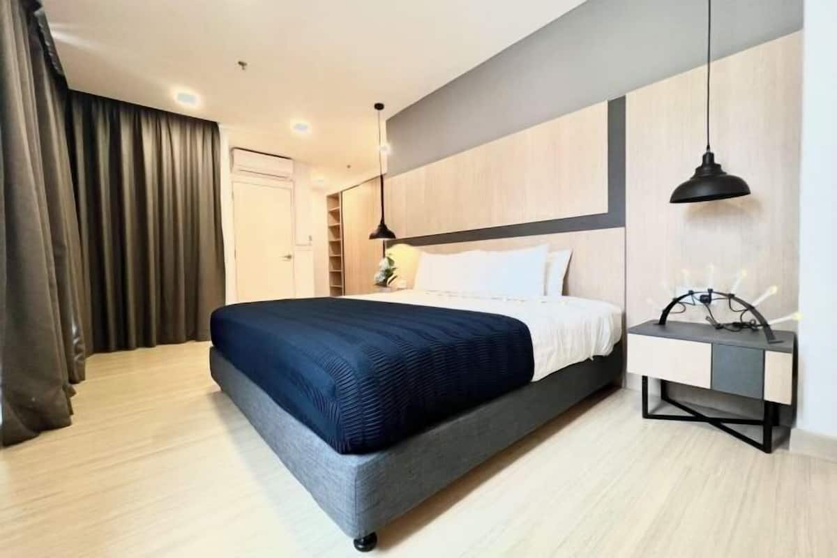 A modern hotel room with a large bed, bedside table, and a nightstand.