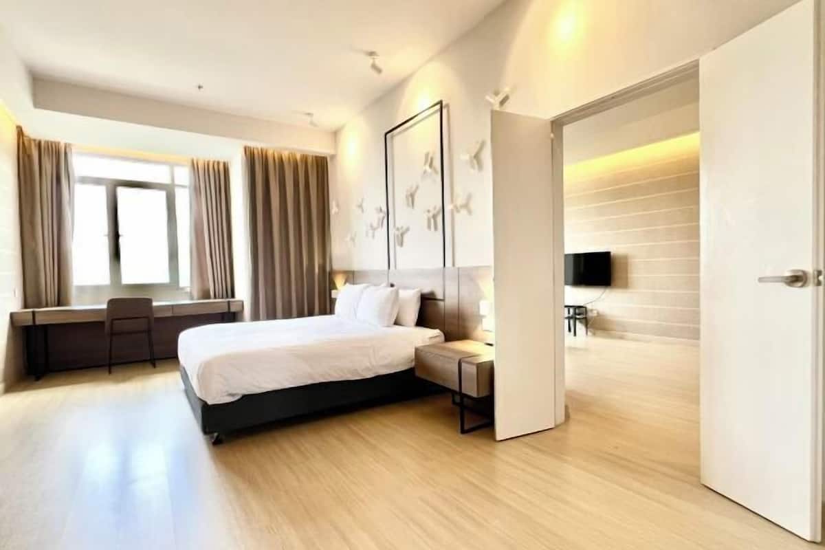 A modern hotel room with a bed, desk, chair, and a television.
