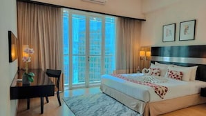 Een hotelkamer met een bed, een bureau, een stoel, een raam met gordijnen en een luchtverkoeler aan de muur.