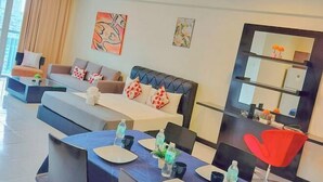 Een moderne woonkamer met een bank, een eettafel voor vier personen en een rode fauteuil.