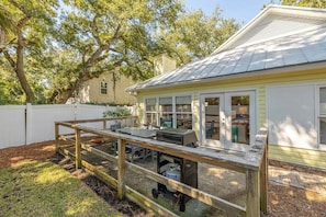 Un jardin avec une terrasse en bois, un barbecue et un espace salon extérieur.