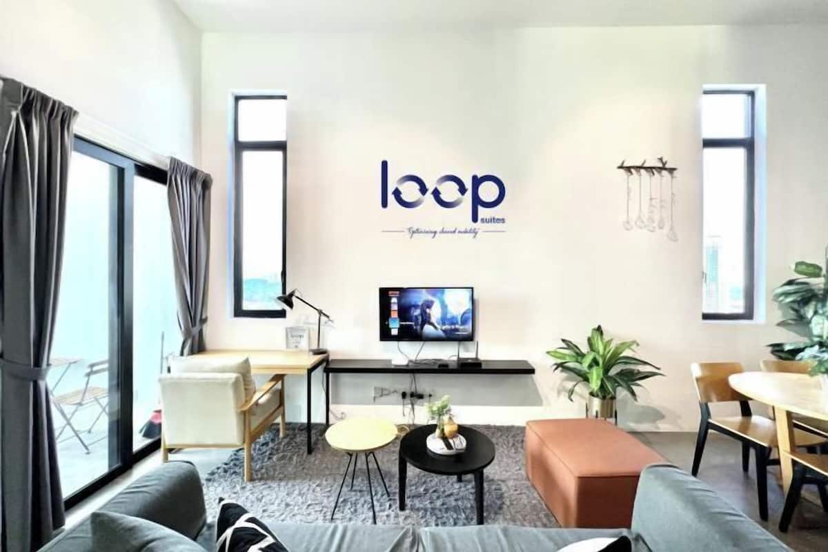 A modern living room with a sofa, coffee table, TV, and a desk.