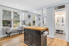 A modern kitchen with a central island, white cabinetry, and large windows.