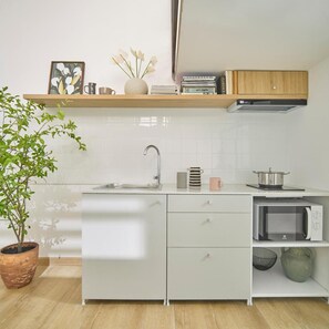 Une cuisine moderne avec des meubles blancs, un four à micro-ondes encastré, un évier et une plante en pot.