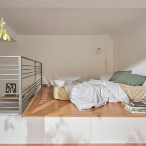 Une chambre avec un lit superposé, une table de chevet avec une lampe et un oreiller vert.
