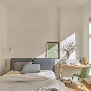 Een slaapkamer met een bed, nachtkastje, lamp en een raam met uitzicht.