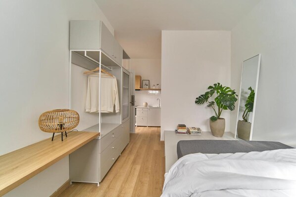 A modern bedroom with a bed, a bedside table, a wardrobe, a mirror, and a potted plant. - Express by M Village Nguyen Du, a brand of Modern Village Lifestyle (Ho Chi Minh City)