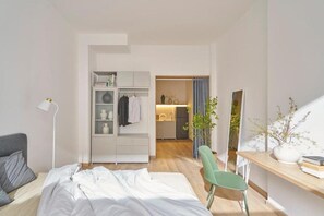 Een slaapkamer met een bed, een bureau, een stoel, een kledingkast en een spiegel.