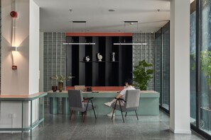 Un comptoir d’accueil moderne avec deux chaises, une cloison en verre et une plante.