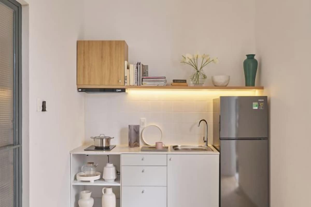 Een moderne keuken met witte kasten, een roestvrijstalen koelkast en een houten bovenkast.