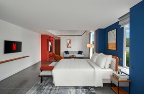 Une chambre d’hôtel moderne dotée d’un grand lit, d’une télévision, d’un coin salon et offrant une vue sur l’extérieur.