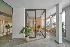 Een modern interieur met een glazen deur naar een eetgedeelte, potplanten en een plafondventilator.