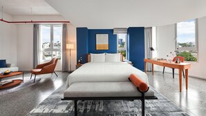 A modern hotel room with a large bed, a desk with chess pieces, and a view of the city. - Express by M Village Nguyen Du, a brand of Modern Village Lifestyle (Ho Chi Minh City)