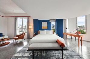Une chambre d’hôtel moderne avec un grand lit, un bureau avec un jeu d’échecs et une vue sur la ville.