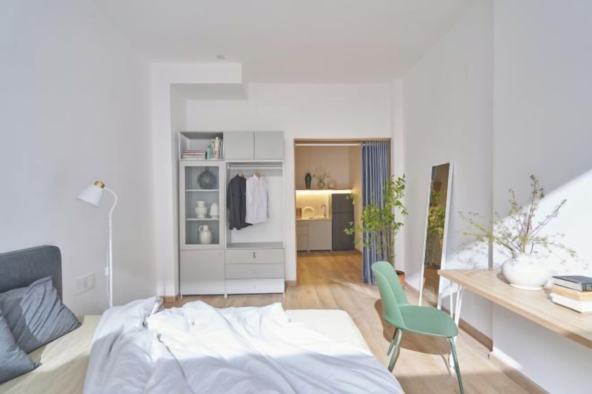 Une chambre à coucher comprenant un lit, un bureau, une chaise, une armoire et un miroir.