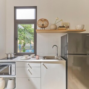 Een moderne keuken met een inbouwoven, een roestvrijstalen koelkast, een raam met uitzicht op groen en een plank met decoratieve objecten.